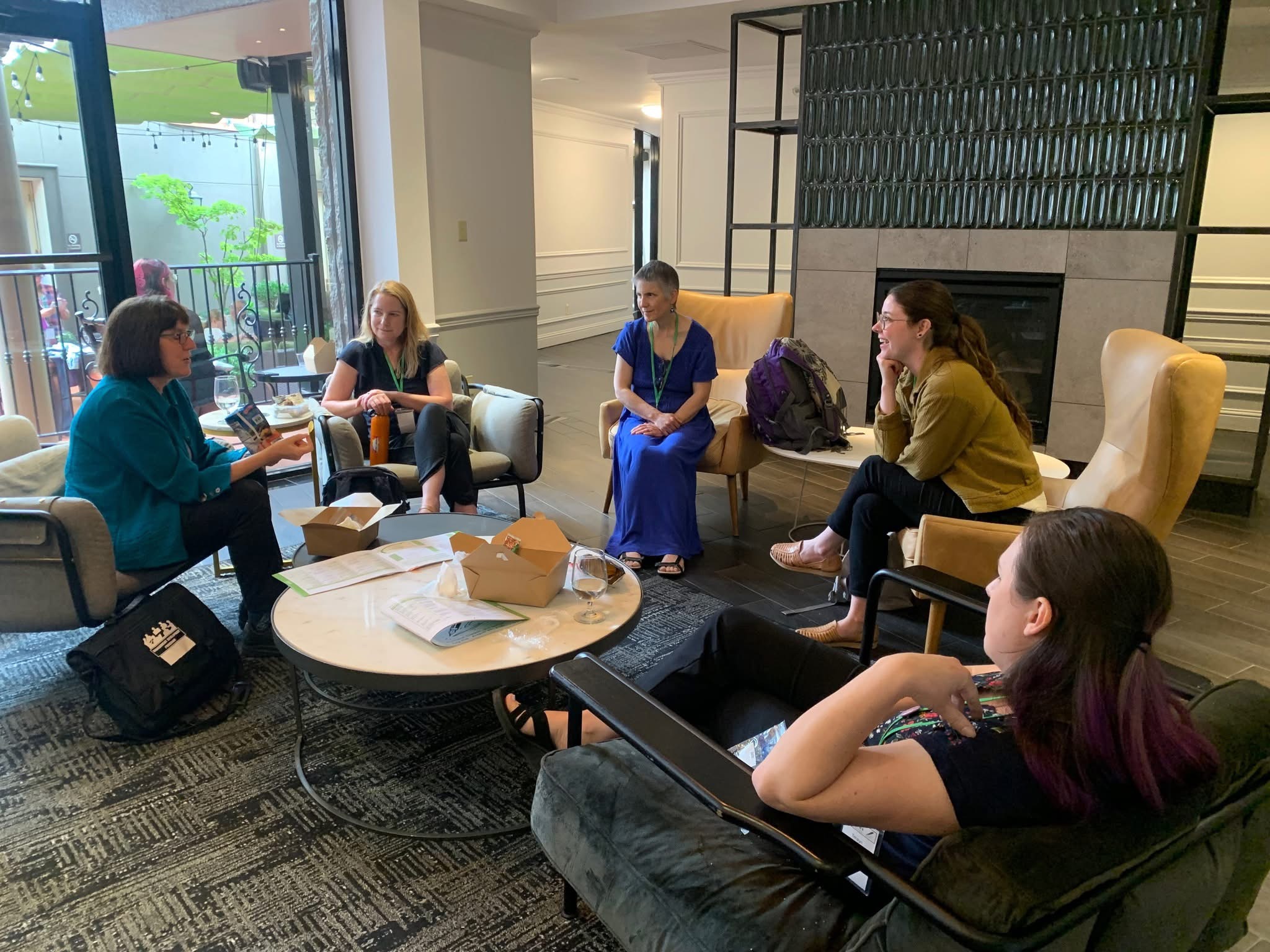Writers gathered around a table chatting by Gail Pasternack